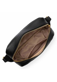 Sac en cuir noir avec fermeture éclair, doté d'un intérieur en tissu beige et d'accents en métal doré, au design épuré et à la texture lisse.