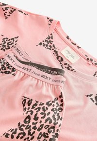 Vaaleanpunainen puuvillapaita, jossa on mustia leopardi-printtitähtiä ja yhteensopivat pyjamat. Ominaisuuksiin kuuluu joustava vyötärö, jossa on brändäys. Rentouttava istuvuus ja pehmeä rakenne.
