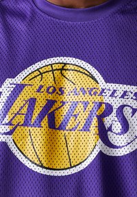 La camiseta de baloncesto de malla morada presenta un gran gráfico de baloncesto amarillo con el texto "Los Angeles Lakers". Tela ligeramente texturizada y transpirable.