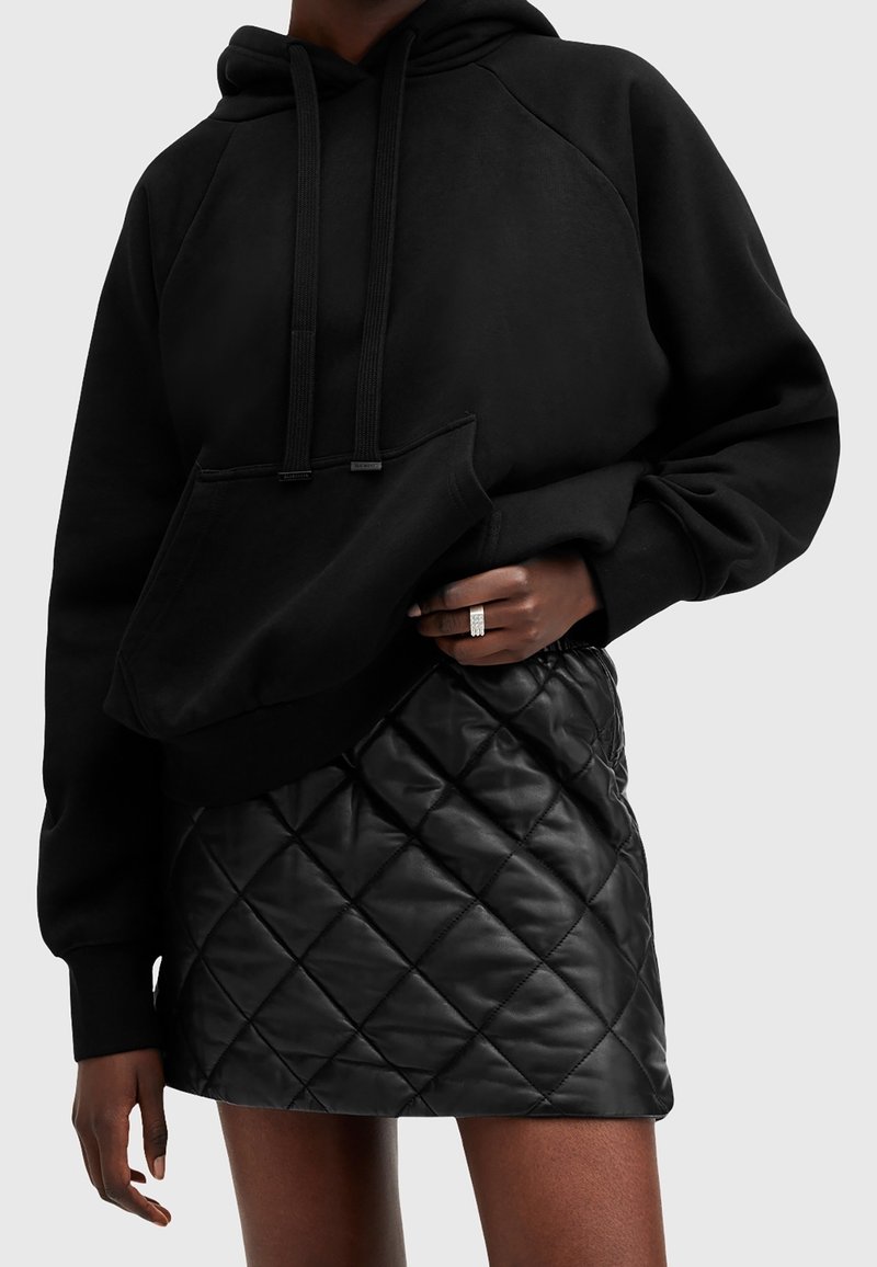 Black cotton hoodie with a front pocket and drawstrings, paired with a black quilted leather mini skirt featuring a diamond pattern.