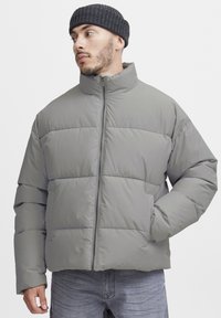 Light gray padded jacket with high collar, full zipper, and side pockets. Smooth texture with horizontal quilted pattern.