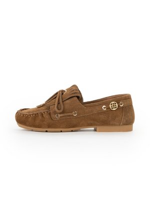 Mocassino in pelle scamosciata marrone con nappine, occhielli decorativi in metallo e suola piatta in gomma, mostrato di profilo su sfondo bianco.