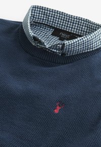 Maglione lavorato a maglia navy con finitura testurizzata, caratterizzato da un colletto a scacchi blu e bianco. Logo di un cervo ricamato in rosso sul petto.