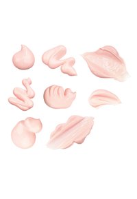 Nove spirali e macchie di crema rosa chiaro su uno sfondo bianco, che variano in forma e texture, mostrando superfici lisce e lucide.