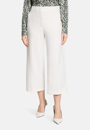 Hvide bukser med brede ben lavet af glat stof, med en midt-lav talje og et rent frontdesign, kombineret med hvide spidse hæle.