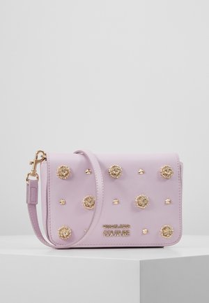 Lilla håndtaske i kunstlæder med guldfarvede nitter, dekorative blomsterdetaljer, justerbar rem og magnetlukning.