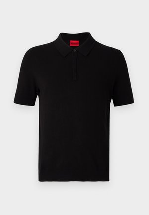 Polo nero realizzato in cotone morbido. Presenta un colletto classico, maniche corte e un'etichetta rossa sulla scollatura. Senza motivi o accenti.