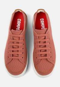 Zapatillas perforadas rosas con una puntera lisa, suela de goma blanca y plantilla roja con "CAMPER" en texto blanco en negrita.