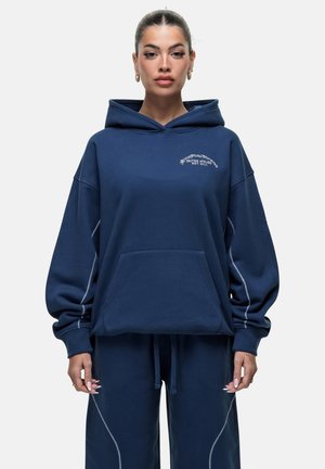 Felpa blu navy in tessuto morbido con tasca a marsupio anteriore, polsini a costine e cuciture a contrasto lungo le cuciture.