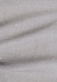 Grijze stof met een gladde textuur, voorzien van verspreide kleine, glanzende versieringen die een gestippeld patroon over het oppervlak creëren.