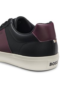 Črno in bordo supergo z gladkimi usnjenimi stranicami, oblazinjenim ovratnikom in belim gumijastim podplatom. Na peti je logotip in barvno blokiran dizajn.