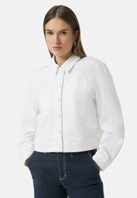 Witte denimjas met een kraag, knoopsluiting aan de voorkant en een enkele borstzak. Korte pasvorm met lange mouwen.