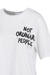 Witte T-shirt met korte mouwen en zwarte druipende tekst "NIET ORDINAIRE MENSEN" op de bovenste linkerkant van de borst.