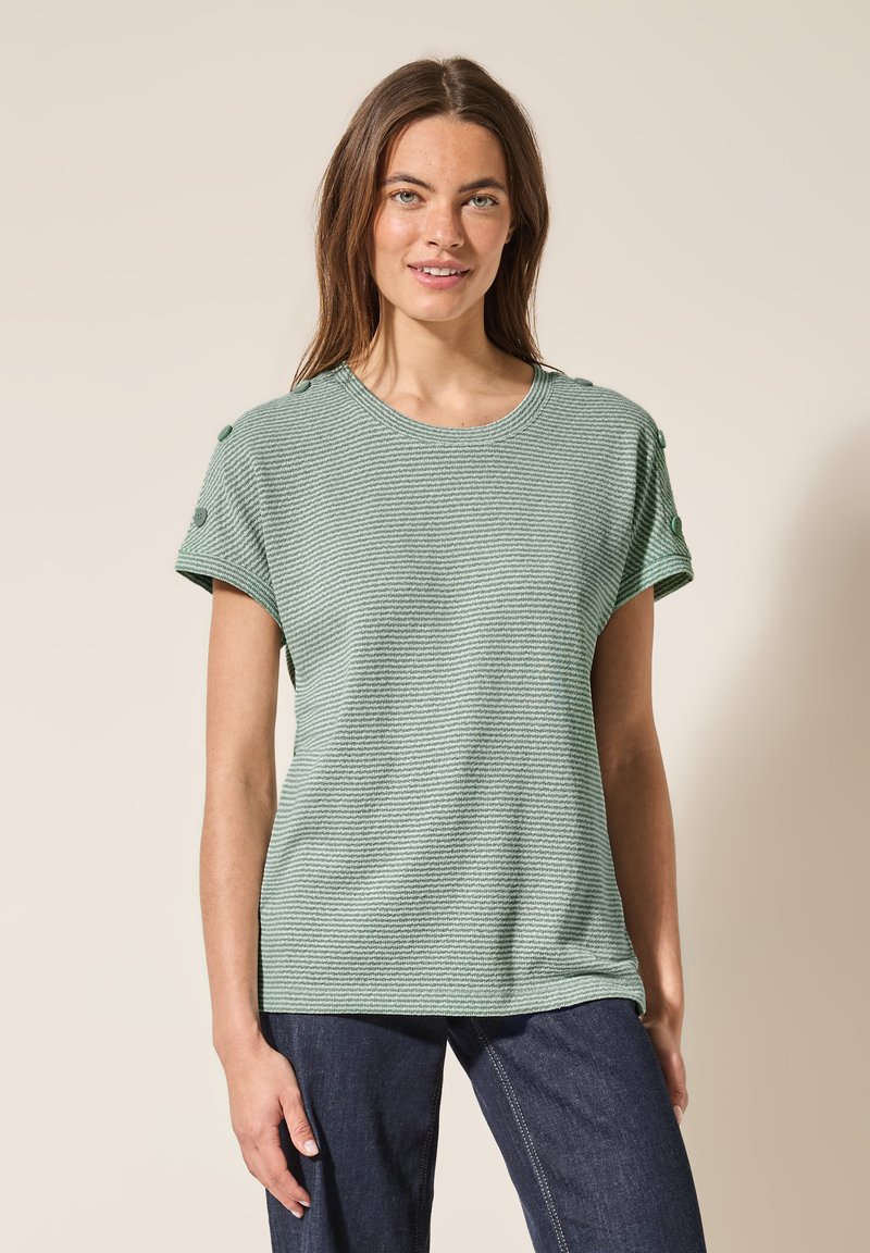 Lys grøn stribet t-shirt med korte ærmer, rund halsudskæring og dekorative knapper på skuldrene. Fremstillet af tekstureret stof.