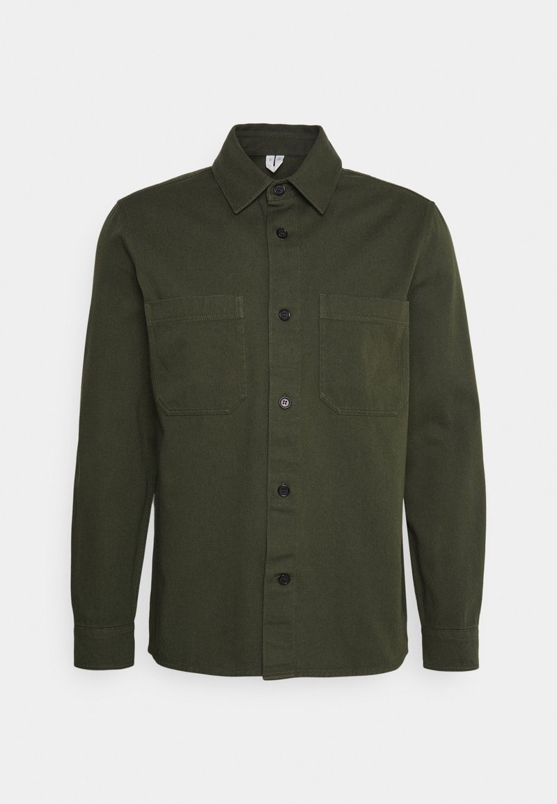 Olijfgroene knoopshirt gemaakt van een gladde stof, met een puntige kraag, twee borstzakken en zwarte knopen.