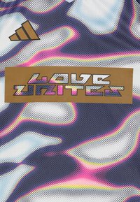 Αθλητικός διχτυωτός ύφασμα με κυματιστό μοτίβο σε μωβ, μπλε και ροζ χρώματα. Περιέχει λογότυπο Adidas και χρυσό ορθογώνιο πάτσι με την ένδειξη "Η ΑΓΑΠΗ ΕΝΩΝΕΙ".