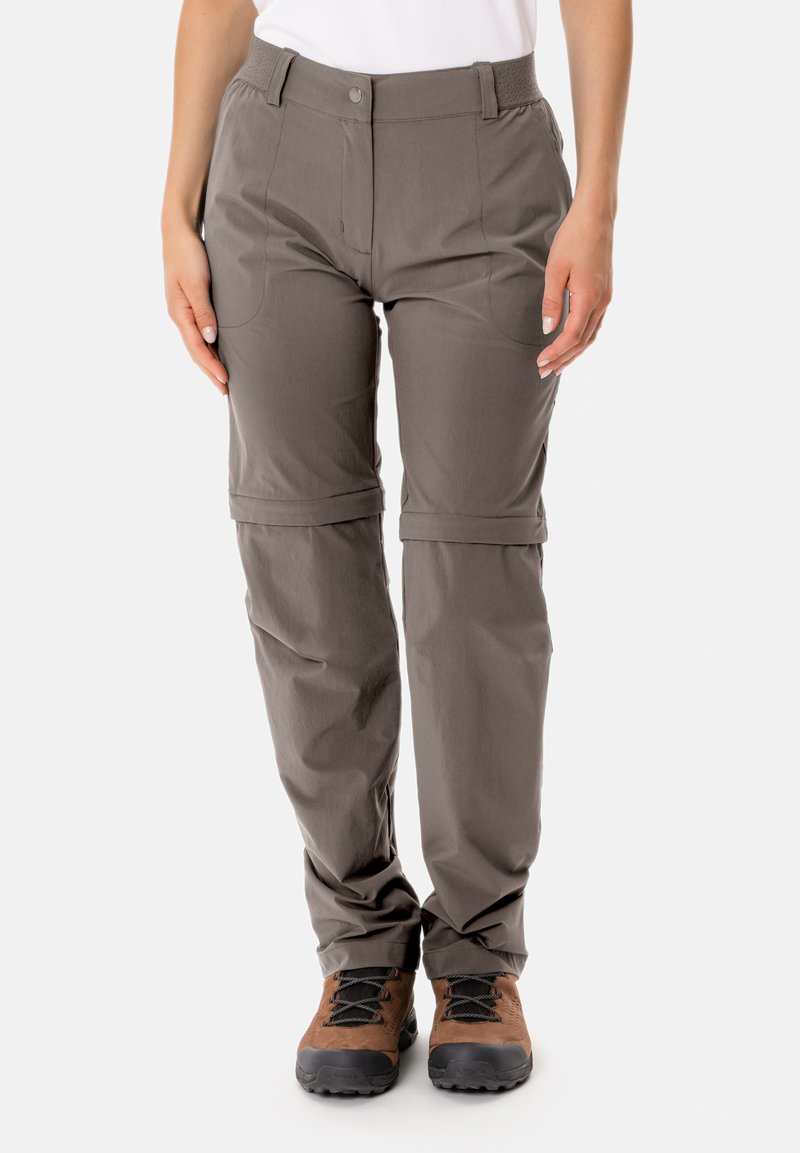 Graue Outdoor-Hosen mit einem Reißverschluss-Feature am Knie, aus leichtem Material, ergänzt durch schräge und Hintertaschen, kombiniert mit braunen Stiefeln.