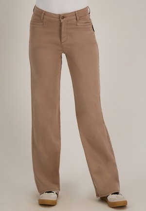 Beige broek met hoge taille en rechte pijpen, gedragen met witte en beige sneakers, getoond op een persoon tegen een effen achtergrond.