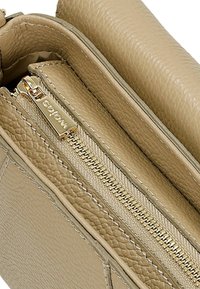 Beżowa skórzana torba wewnątrz z kieszenią na zamek, prezentująca gładką teksturę i złoty zamek błyskawiczny z metką marki, dodatkowo z przeszyciami.