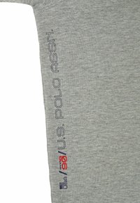 Camisa de manga larga gris con texto bordado en azul oscuro "U.S. POLO ASSN." y "USA 90" en rojo, con una textura suave de mezcla de algodón.