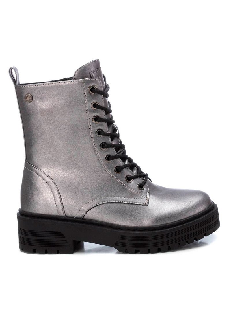 Botines metálicos plateados con cordones, suela de goma negra, punta redonda y cordones negros en contraste; cuenta con una lengüeta en el talón para facilitar el uso.