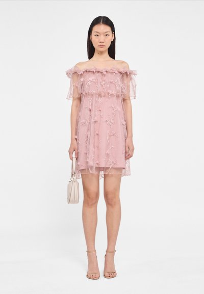 Off-shoulder roze kanten jurk met bloemenborduursels, transparante overlay, gerimpelde halslijn en doorzichtige korte mouwen, gecombineerd met een beige handtas.