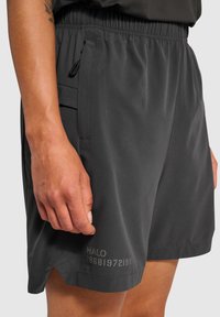 Ciemnoszare spodenki sportowe z elastycznym paskiem, bocznymi kieszeniami i ozdobnym nadrukiem z napisem "HALO 19681972198" blisko dolnej krawędzi.