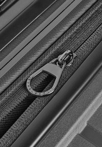 Schwarze erweiterbare Reisetasche mit Reißverschluss und Metall-Zipper, der mit der Gravur "ERWEITERBAR" versehen ist. Texturiertes schwarzes Gewebe mit Fischgrätmuster und glatten Kunststoffakzenten.