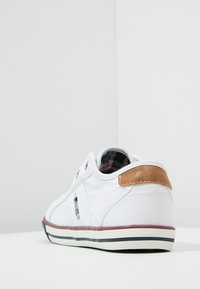 Weiße Leinenschuhe mit braunem Lederakzent, niedrigem Schnitt, abgerundeter Form und Gummisohle mit einem maroon- und navyblauen Streifen.