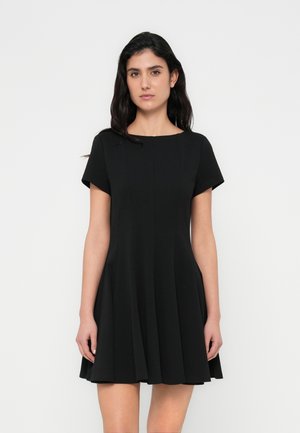 Robe noire à manches courtes, col rond et jupe évasée. Confectionnée en tissu lisse avec des coutures verticales subtiles.