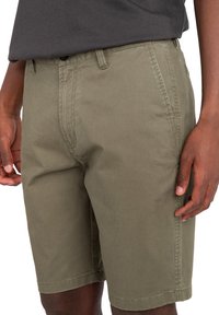 Olivgröna shorts i bomull med en avslappnad passform, som har sidofickor, sydda sömmar och rak skärning.
