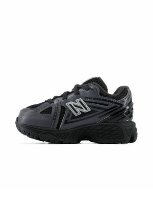 Sort og mørkegrå atletikskos med mesh-stof, tyk sål, snørebånd og New Balance-logo på siden.
