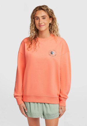 Koralni pulover z okrolim izrezom, dolgimi rokavi in rebrastimi manšetami. Na sprednji strani ima grafiko in je kombiniran s svetlo zelenimi kratkimi hlačami.