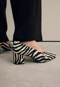 Zebra print block-heeled pumps with a pointed toe; made of textured fabric in black and cream; featuring a sturdy, chunky heel.