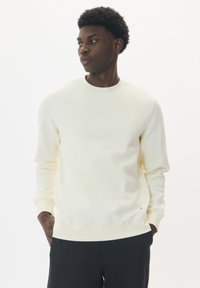 Crèmekleurige sweatshirt van zacht materiaal, met een ronde hals, lange mouwen en ribgebreide manchetten, voorzien van een klein logo op de zoom.