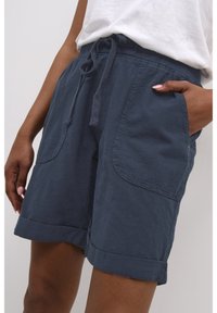 Shorts in misto lino blu navy con vita regolabile, dotati di grandi tasche laterali e risvolti, con un dettaglio di superficie tessurizzata.