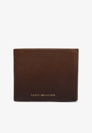 Brun læderpung med syede kanter og gyldt Tommy Hilfiger-logo centreret foran mod en hvid baggrund.