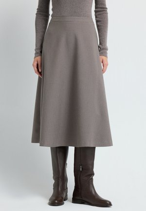 Una gonna a quadri grigia fino al ginocchio con un design svasato, abbinata a stivali in pelle marrone alti fino al ginocchio con cerniere laterali.