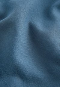 Strukturierter Stoff in gedämpftem Blauton, mit feinem webmuster. Weiche Oberfläche mit leicht reflektierender Qualität.