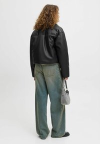 Czarna krótka skórzana kurtka, luźny krój, gładka faktura; połączona z jasnoniebieskimi, workowatymi dżinsami, z wyblakłym, swobodnym fasonem.