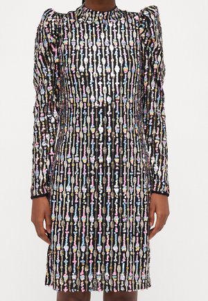 Black long-sleeve dress with vertical multicolored sequin stripes and puffed shoulders, worn by a person with hands relaxed at sides.