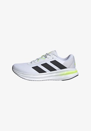 White athletic shoe with black stripes and green accents, featuring a textured mesh upper, lace-up design, and cushioned sole for support.