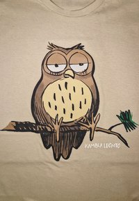 Ilustrace hnědé sovy na béžovém tričku, s zvýrazněnýma očima a kulatým tělem s černými akcentními liniemi, sedící na větvi.