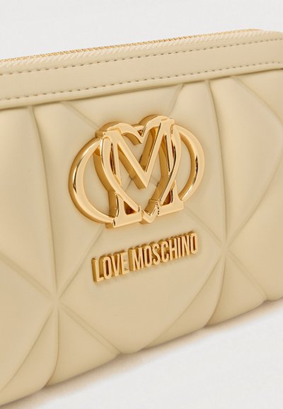 Portefeuille matelassé beige en matériau lisse, présentant un logo double cœur en ton or et un détail embossé "LOVE MOSCHINO".
