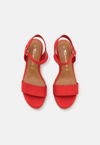 Sandali in suede rosso con due ampie cinghie, una cinghia alla caviglia con fibbia e una soletta dal tono naturale. La taglia 37 è visibile all'interno.