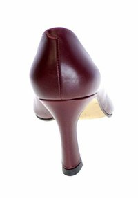 Una singola scarpa con tacco alto in pelle di un intenso rosso scuro vista da dietro, con tacco affusolato e cuciture visibili.