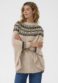 Brede trui in beige met donkergroene geometrische patronen op de schouderpassen en manchetten. Losse pasvorm met brede mouwen, gemaakt van zacht materiaal.