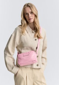 Borsa a tracolla rosa in pelle testurizzata, con motivo intrecciato e forma rettangolare. Tracolla regolabile e chiusura con zip.