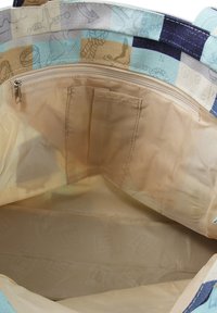 Canvas draagtas met een geweven buitenkant in lichtblauw en beige kleuren, en een met rits afsluitbaar vakje aan de binnenkant voor organisatie. Glad, textuurachtig voering.