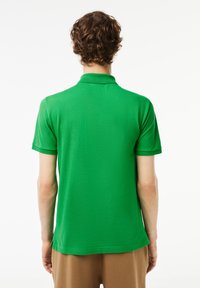 Green polo shirt with short sleeves, a flat collar, and a straight hem. Made of breathable fabric with a smooth texture.
